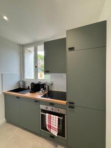 a kitchen with green cabinets and a sink at Portes de Paris RER C à 2 min WiFi & Parking Inclus in Choisy-le-Roi +28 photos