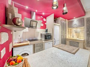une cuisine aux murs roses et une table avec un bol de fruits dans l'établissement Les Portes du Château Beaucairois, à Beaucaire
