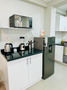 a kitchen with a black counter and a refrigerator at Las Viñas - Departamentos Privados in Ica