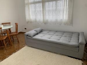 a couch in a living room with a table and a window at Apartamento Vista Mar in Peruíbe