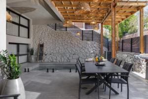 patio ze stołem i krzesłami oraz kamienną ścianą w obiekcie Diamond in the Desert- for families w Ejlat