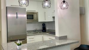 a kitchen with white cabinets and a stainless steel refrigerator at Hermoso edificio Frente al mar con gran terraza y hermosas vistas in Las Palmas de Gran Canaria