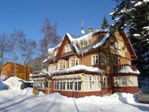 a large wooden house with snow on top of it at Hotel Diana in Špindlerův Mlýn