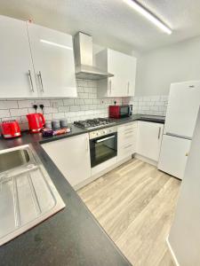 a kitchen with white cabinets and a wooden floor at CMK Home + Garden, Train station, The Hub 5 mins in Milton Keynes