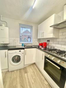 a kitchen with white cabinets and a washer and dryer at CMK Home + Garden, Train station, The Hub 5 mins in Milton Keynes