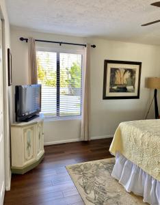 a bedroom with a bed and a tv and a window at Cypress Retreat in Fort Myers