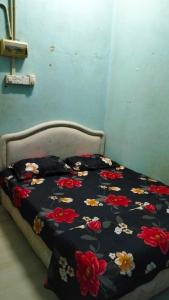 a bed with a black blanket with flowers on it at Hostel Dena moon inn 3 in Kota Bharu