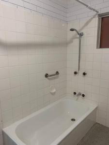 a white bathroom with a tub and a shower at Bribie Get away in Bongaree