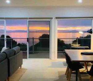 een woonkamer met een tafel en uitzicht op de oceaan bij Beachfront House - Hot Tub, Ocean Views, Private Beach Pathway in White Beach