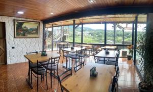 a restaurant with tables and chairs in a room with windows at Cabinas Vista Al Golfo in Monteverde Costa Rica