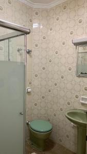 La salle de bains est pourvue de toilettes vertes et d'un lavabo. dans l'établissement Apartamento Vista Mar, à Peruíbe