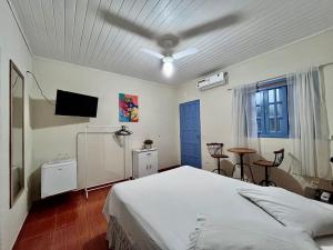 a bedroom with a white bed and a tv at Recanto Toca das Plantas de Ilhabela I in Ilhabela