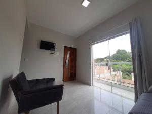 a living room with a chair and a large window at Apartamento Aconchego nas Montanhas, em Cunha-SP in Cunha