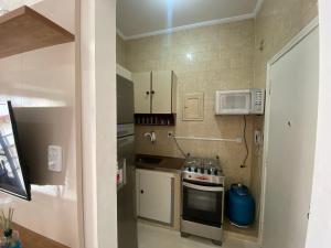 uma pequena cozinha com fogão e micro-ondas em Apto Santos Gonzaga em Santos