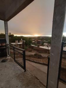 uma vista para o pôr-do-sol a partir de um edifício com uma cerca em ENCANTO SERRANO em Villa Carlos Paz