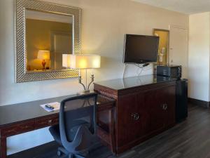 Habitación de hotel con escritorio, TV y silla en Quality Inn Alachua - Gainesville Area, en Alachua