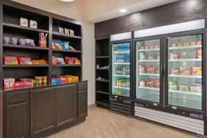 a kitchen with a refrigerator and shelves with food at Comfort Suites Idaho Falls in Idaho Falls