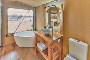 ein Badezimmer mit einer Badewanne, einem Waschbecken und einem Spiegel in der Unterkunft Willow Wood Glamping Retreat in Broadwater