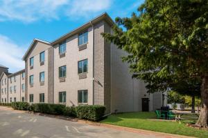 un edificio de apartamentos con un árbol delante de él en Quality Inn & Suites Roanoke - Fort Worth North, en Roanoke