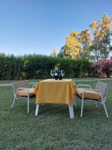 a table and two chairs with a yellow table and two glasses at BODEGA Y ALOJAMIENTO DON VEGA in Tinogasta