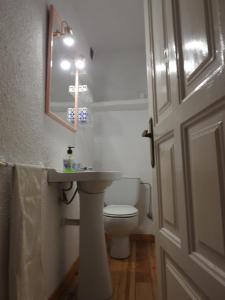 a bathroom with a toilet and a sink and a cross on the wall at La Majada del Puente in El Royo