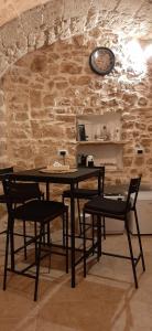 einen Tisch und Stühle in einem Zimmer mit einer Steinmauer in der Unterkunft Dimora Cleó in Putignano