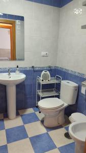 a blue and white bathroom with a toilet and sink at Alojamientos Turísticos La Palmera in Cúllar-Vega