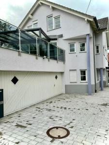 une maison blanche avec de nombreuses fenêtres et une allée. dans l'établissement flexible, schöne und gut aussehende Feriensuite (für Stadtliebhaber, Shopper, Naturliebhaber und Entspannungssuchende), à Reutlingen