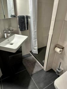 a white bathroom with a sink and a shower at flexible, schöne und gut aussehende Feriensuite (für Stadtliebhaber, Shopper, Naturliebhaber und Entspannungssuchende) in Reutlingen