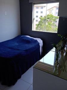 a bedroom with a blue bed and a window at Apartamento aconchegante in Ilhéus