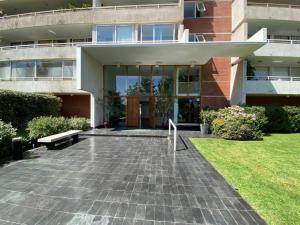 un bâtiment avec un banc devant lui dans l'établissement Alto Las Condes - A pasos del Mall - Excelente y cómodo Departamento p/2 personas, à Santiago