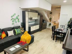 a living room with a black couch and a kitchen at Bien comunicado, acogedor y confortable in Coslada