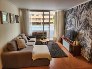 un salon avec un canapé et une télévision dans l'établissement Alto Las Condes - A pasos del Mall - Excelente y cómodo Departamento p/2 personas, à Santiago