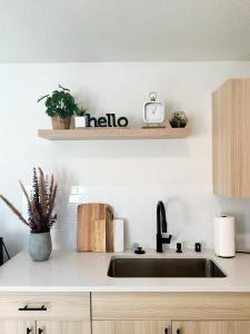 a kitchen sink with a hello sign on a shelf at Brand New Modern Apartment in Vancouver