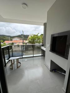 a living room with a view of a balcony with a television at Conchas das Caravelas in Governador Celso Ramos