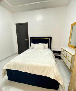 a bedroom with a bed and a dresser and a mirror at Urban Retreat Luxury Shortlet Apartment Lekki Lagos in Lekki