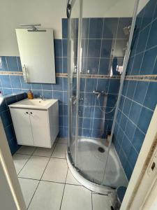 La salle de bains est pourvue de carrelage bleu, d'une douche et d'un lavabo. dans l'établissement Calme, lumineux avec balcon, à Toulouse