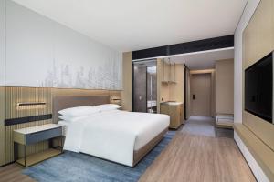 a bedroom with a white bed and a flat screen tv at Courtyard by Marriott Beijing Changping in Beijing