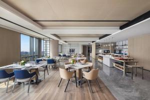 a restaurant with tables and chairs and a kitchen at Courtyard by Marriott Beijing Changping in Beijing