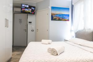 una camera da letto con un letto bianco e asciugamani di Residenza Gioiello - Comfort & Suites a Milano a Milano