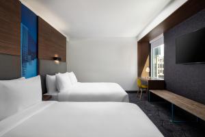 Habitación de hotel con 2 camas y TV de pantalla plana. en Aloft Denver Downtown en Denver