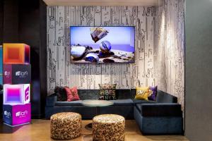 a living room with a couch and a tv on a wall at Aloft Denver Downtown in Denver