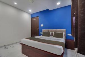 a bed in a room with a blue wall at Collection O Hotel Miraaz in Gwalior