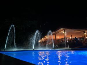 a fountain in a swimming pool at night at Virly’z Top View Resort 