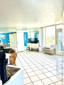 a living room with a tv and a tiled floor at Beach Happy - Ocean View at Symphony Beach Club in Ormond Beach