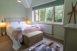 a bedroom with a bed and a chair and two windows at 2 The Winnings - Stunning Cottage on a Country Estate in Worksop