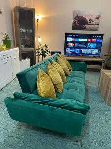 - un canapé vert avec des oreillers jaunes dans le salon dans l'établissement Veľký apartman, à Karlova Ves