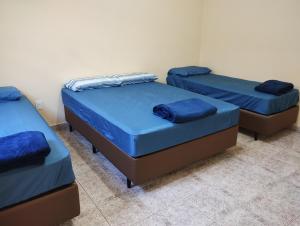three beds in a room with blue sheets at Casa de Bençãos de Aparecida. in Aparecida