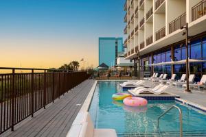 a swimming pool with chairs and a building at Moxy Virginia Beach Oceanfront in Virginia Beach