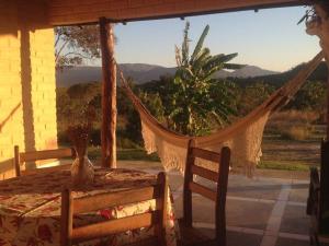 een veranda met een hangmat, een tafel en een raam bij Chácara Canto da Mata in Cavalcante